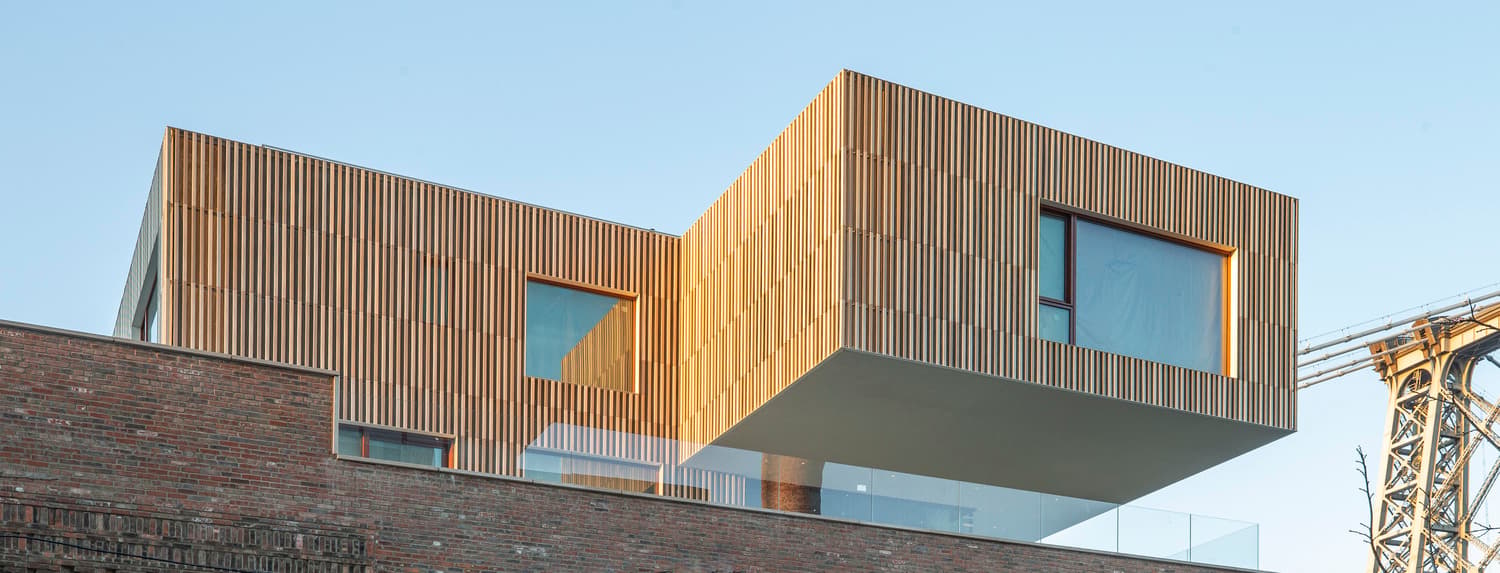 Angular weathered-metal building projecting above an industrial site