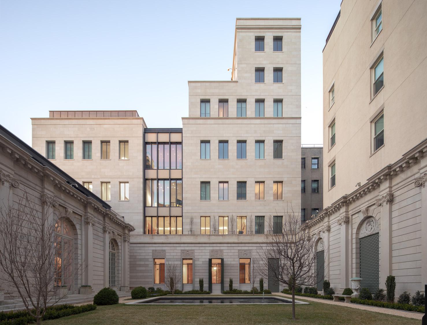 Quiet masonry courtyard framed by an existing civic building