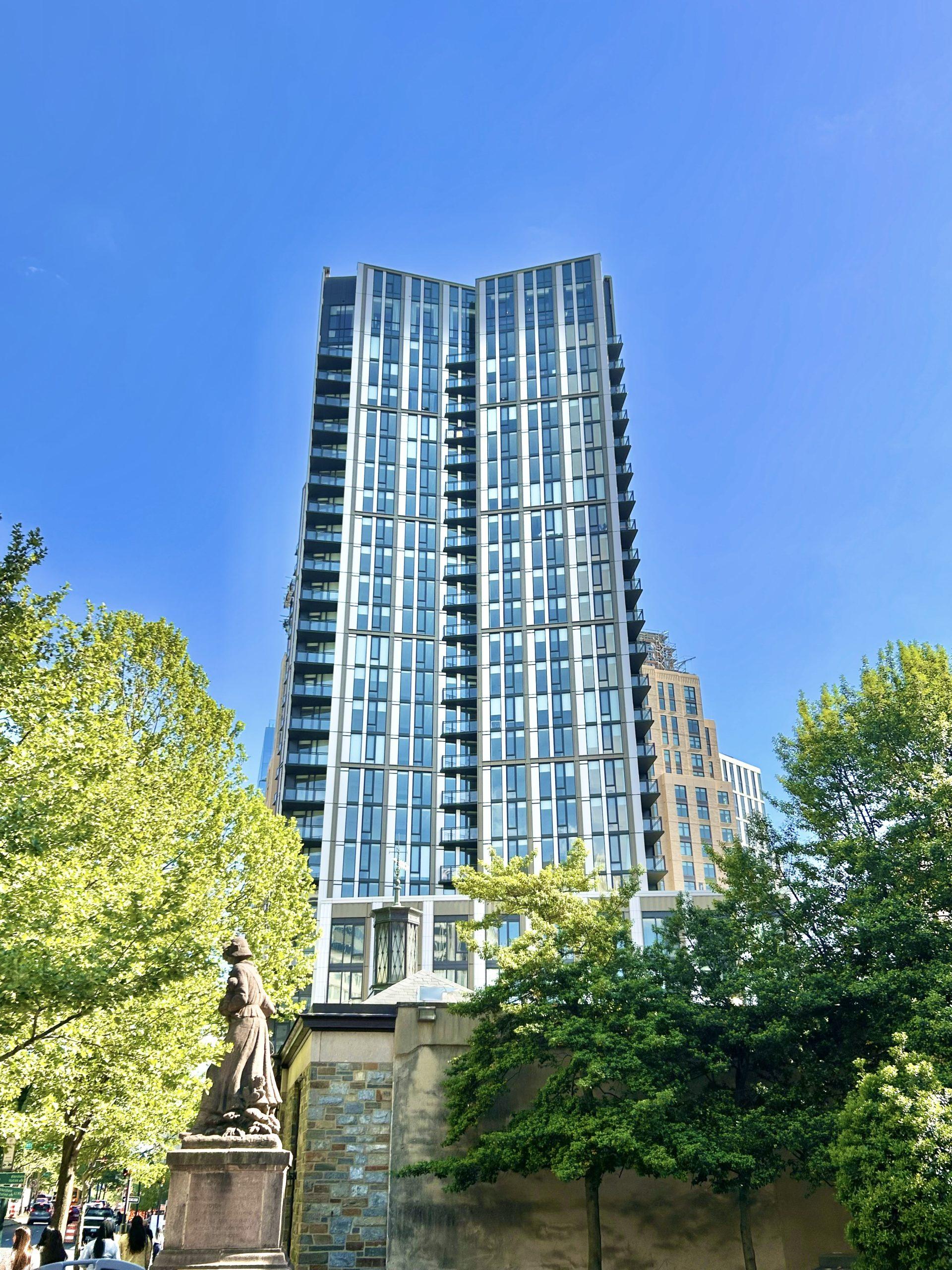 Completed residential tower seen through mature trees