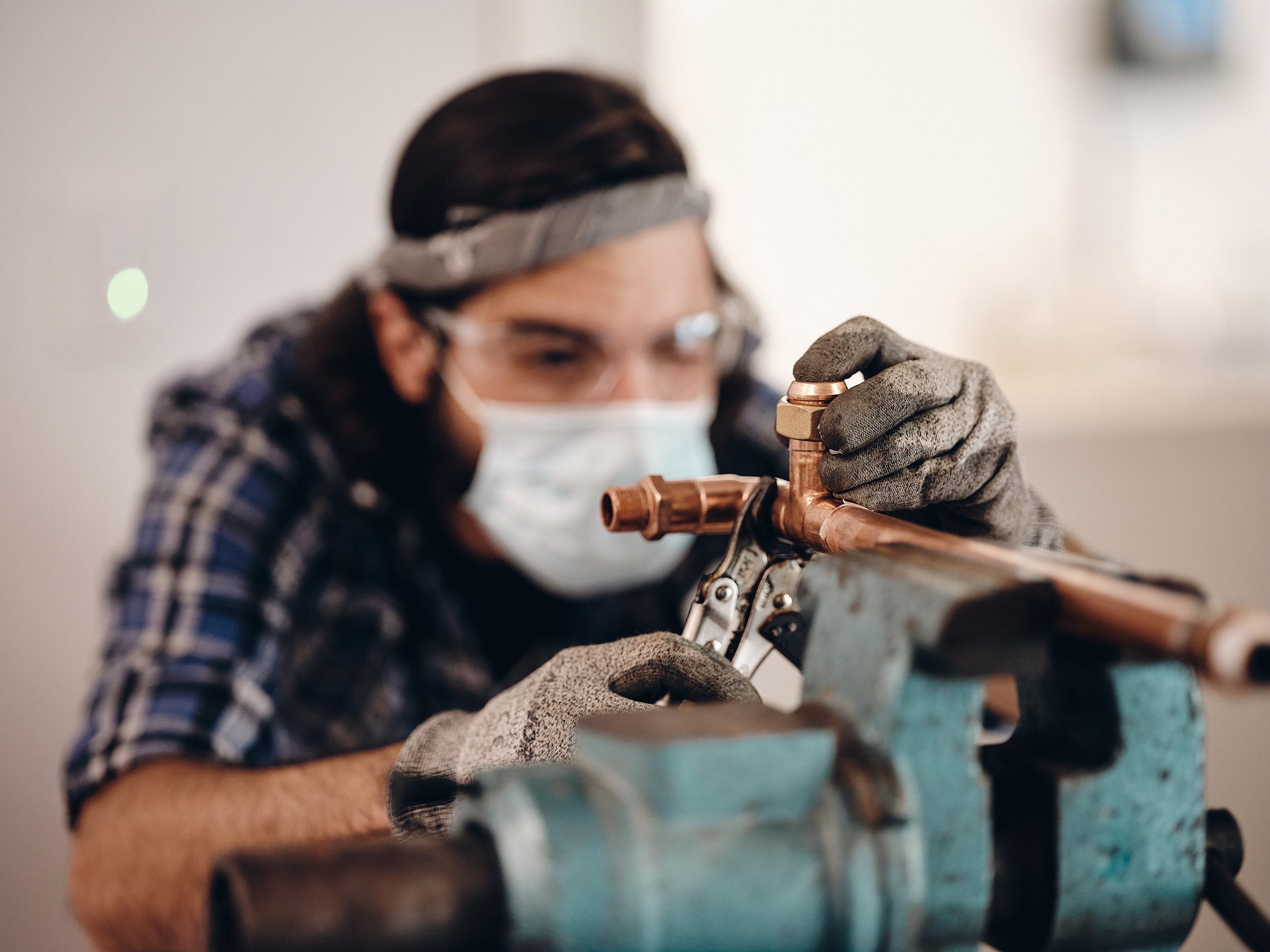 Fabricator working at a bench beside a steel assembly
