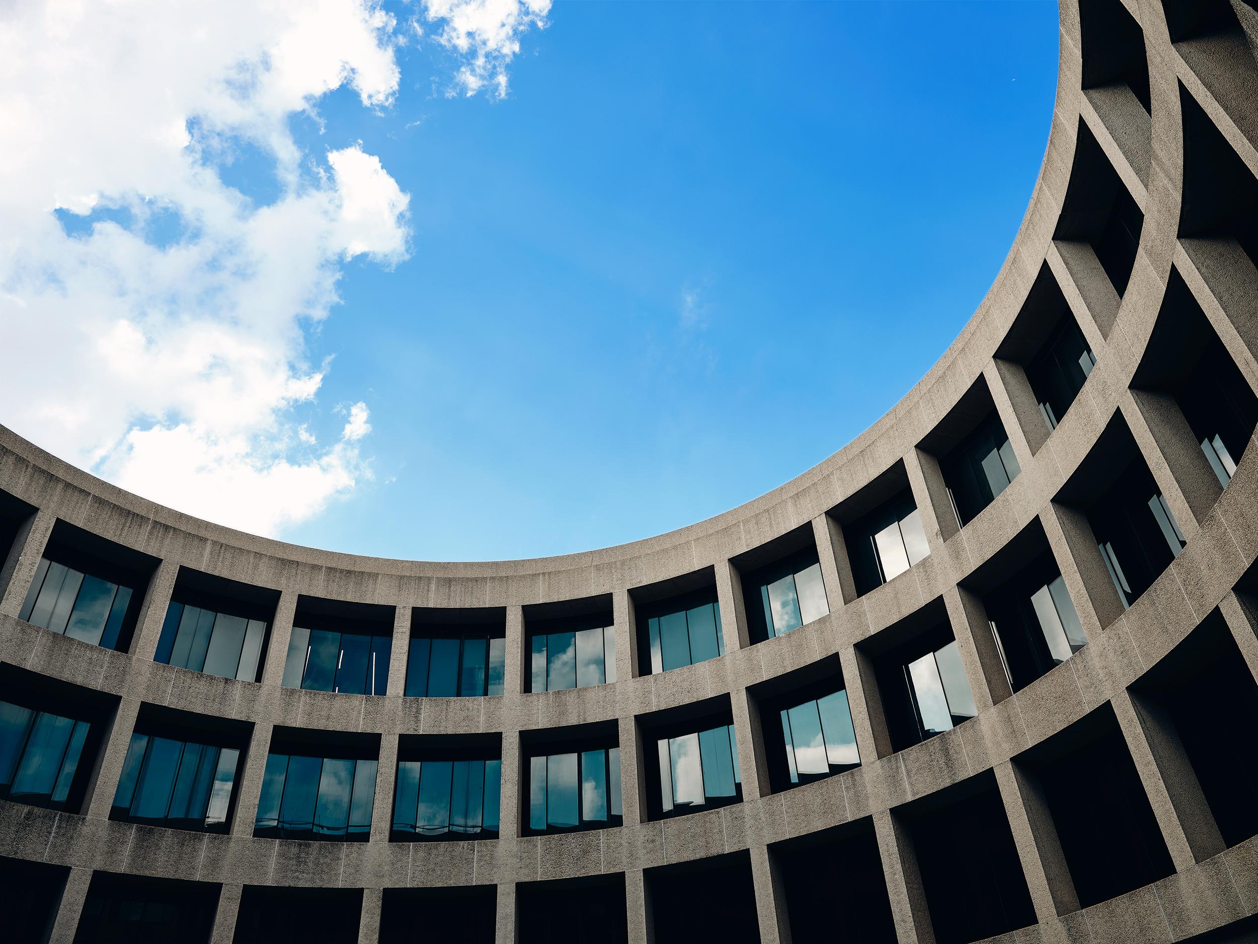 Curved concrete museum facade seen against a blue sky